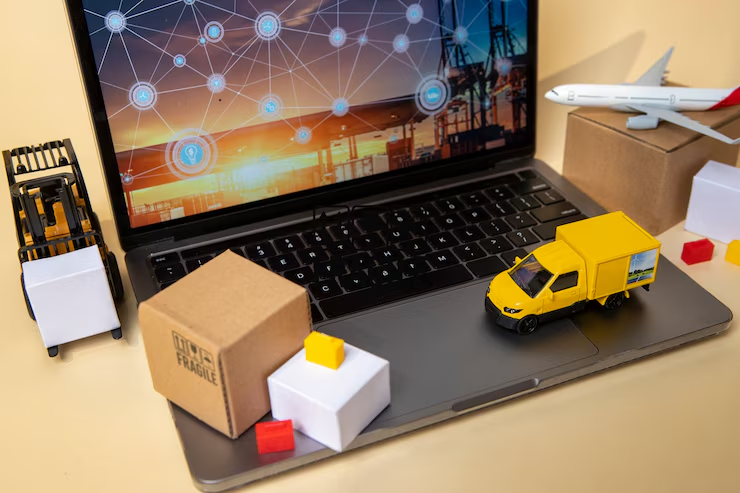 Laptop displaying a digital network with miniature delivery truck, boxes, and airplane, symbolizing e-commerce and logistics management.