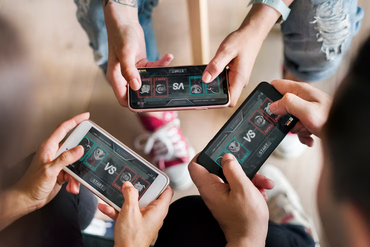 Overhead shot of multiple people holding smartphones and playing a mobile game together, demonstrating multiplayer or social gaming.