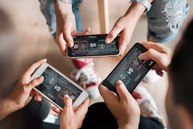 Overhead shot of multiple people holding smartphones and playing a mobile game together, demonstrating multiplayer or social gaming.