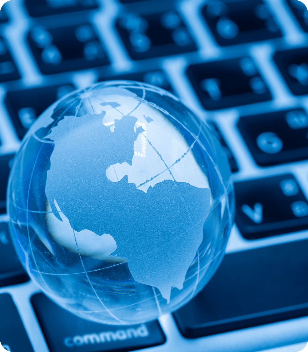 A clear glass globe showing continents resting on a laptop keyboard, symbolizing global connectivity or technology.